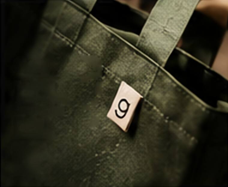 Olive canvas tote bag handle and body with a woven label.