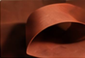 A curl of terracotta paper with a soft textured surface.
