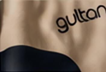 The Gultan wordmark printed on natural fabric beside a navy curve.