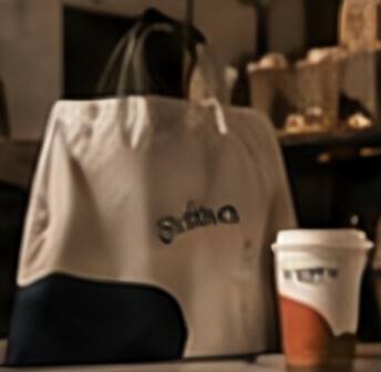 A natural canvas Bayleaf tote bag and a takeaway cup.